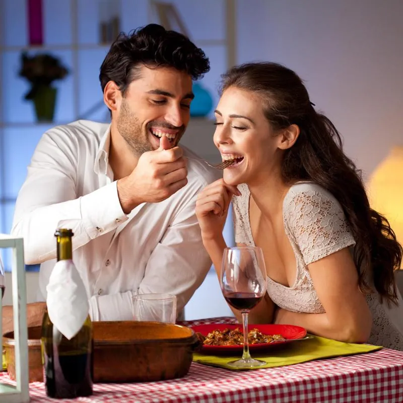 Laughing couple sharing food at a checked-tablecloth table